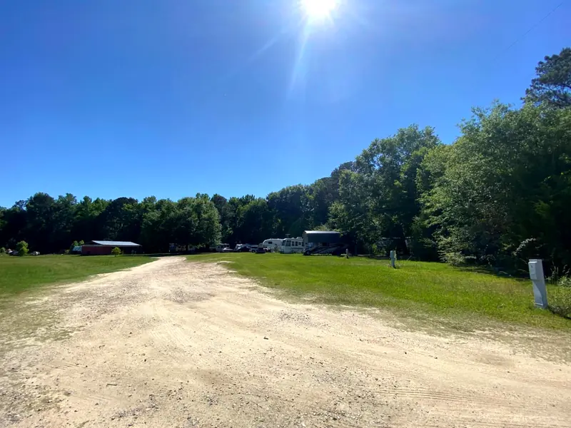 A wide gravel pad with campers and outbuildings in the distance