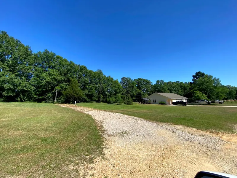 A gravel drive curving through the grass toward the back of the property